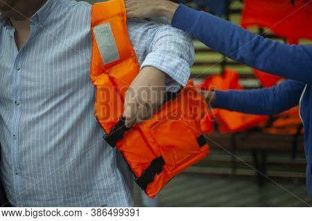 Puts On A Life Jacket. A Man Prepares To Swim On The Lake. Compliance With Safety Measures On The Wa