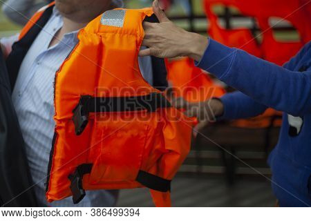 Puts On A Life Jacket. A Man Prepares To Swim On The Lake. Compliance With Safety Measures On The Wa