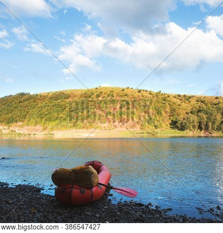 Orange packraft rubber boat with backpack on a river. Packrafting. Active lifestile concept