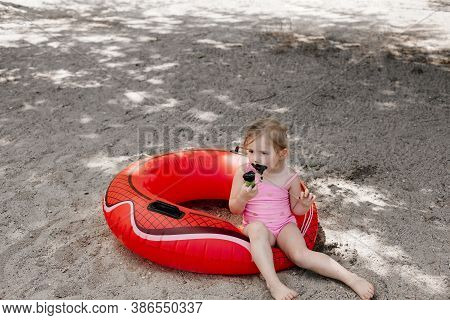 Little Girl Eating Black Ice Cream On The Beach. Lifebuoy. Dirty Child
