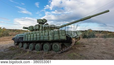 A Side Shot Of Russian Tank T-64 In The Field. Blue Cloudy Sky As A Background.