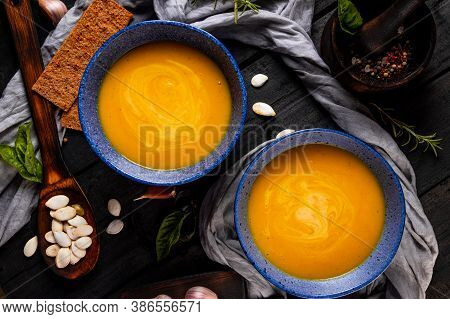 Two Plates Of Hot Pumpkin Soup On A Black Wooden Table, Top View