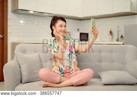 Woman Sitting Sofa Home Phone Holding Hand Makes Selfie Photographs Broadcasting Smile Positive