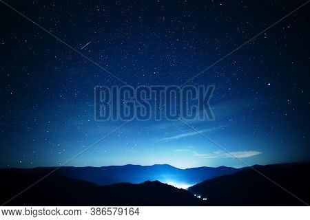 Starry Sky Over Mountains Panorama With City Lights Below