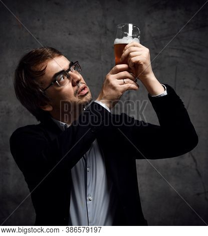 Middle-aged Man In Stylish Official Clothing Jacket And Shirt Holds Up A Glass Of Drink Craft Beer A