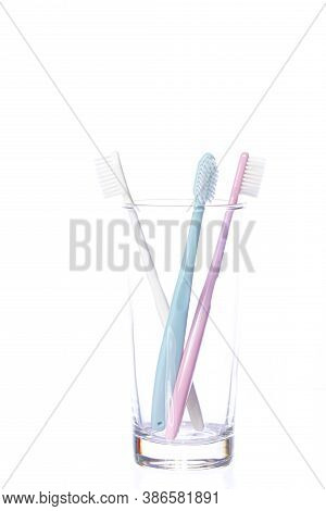 Three Colorful Plastic Pastel Shades Toothbrushes In Glass Isolated On White Background. Love Triang