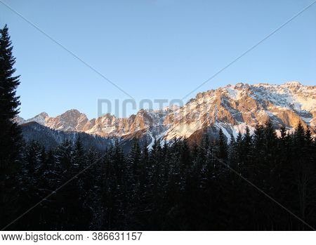 Landscape With Snowy Mountains And Forest Against A Blue Sky