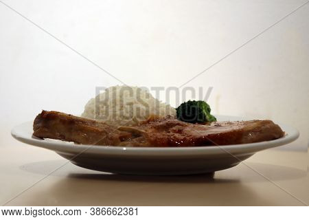 Pork Chop Steak White Rice And Green Broccoli In The Dish On The Wooden Table. Steak Is High Quality