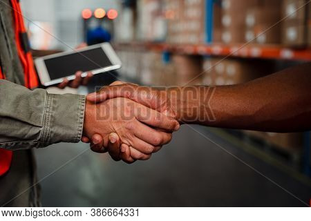 Close Up Of Caucasian An Ethnic Male Co-workers Shaking Hands After Making Successful Deal In Wareho