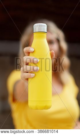 Young Woman In Yellow T-shirt Holding Yellow Reusable Bottle
