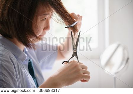 A Woman Looking Concern For Herself Haircut By Scissors And Comb At Home During Covid-19 Pandemic, A