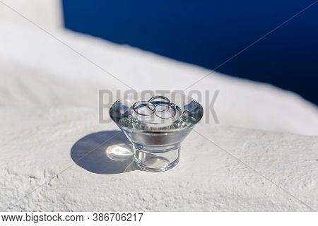 Close-up Wedding Rings, Engagement Ring, In A Vase On A Blue And White Background Sea, In Greece San