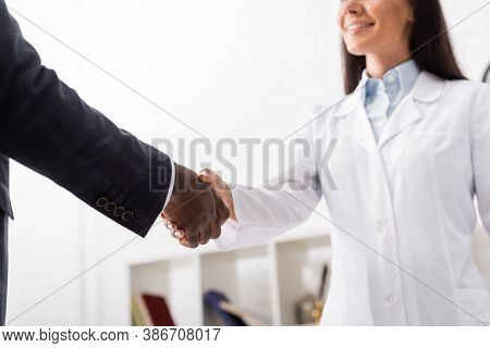 Cropped View Of Doctor In White Coat Shaking Hands With African American Patient