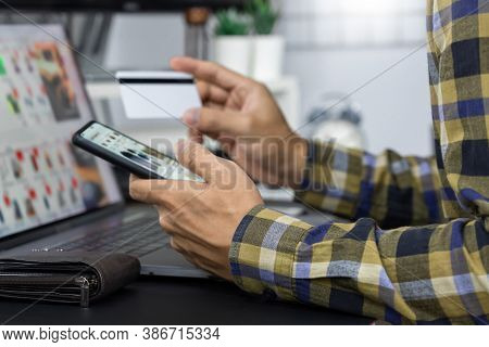 Asian Man Holding Credit Card To Online Shopping With Laptop Computer And Entering Security Code, In