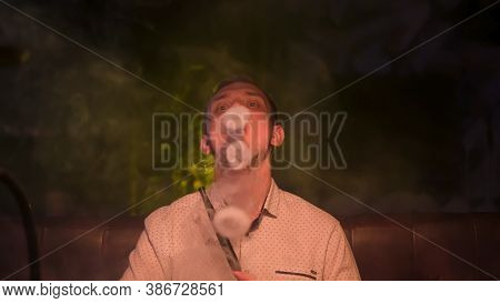 Caucasian Man Exhaling A Fog Cloud And Chilling. Media. Front View Of Handsome Young Guy Smoking Hoo
