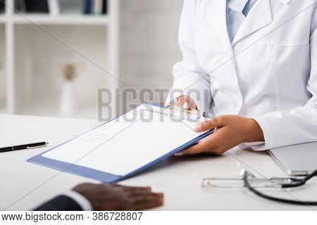 Cropped View Of Doctor Holding Clipboard With Insurance Claim Form Near African American Patient