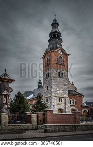 Old Stone And Brick Church With Clock Tower In Bialka Tatrzanska. Dark, Moody Storm Clouds And Drama
