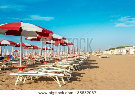 roten und weiÃŸen Sonnenschirmen und Sunlongers am Sandstrand