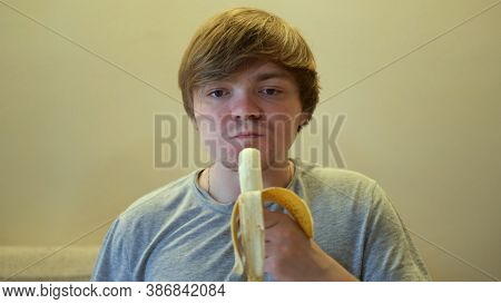 Portrait Of An Adult Hungry Man Who Eating A Ripe Banana With An Appetite. Concept. Front View Of A 