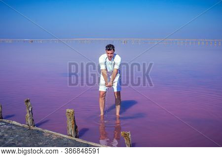 Brunet Man Relaxing On Pink Salty Sivash Lake Near Azov Sea, Colored By Microalgae Dunaliella Salina