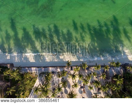 Aerial Shot Of A Luxury Hotel On A Beach First Line With Palm Trees Drops Their Shades On A High Tid