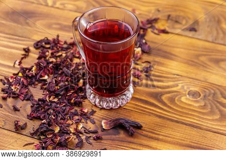 Glass Cup Of Red Hibiscus Tea (carcade, Roselle) On Wooden Table