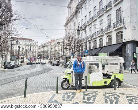 7 March 2018: Lisbon, Portugal - Tuk Tuk Driver Wrappede Up Warm, Waiting For Business On The Street