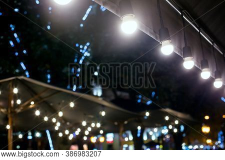 Textile Umbrella With Wooden Frame And String Lights Glowing With White Light On Backyard Terrace, C
