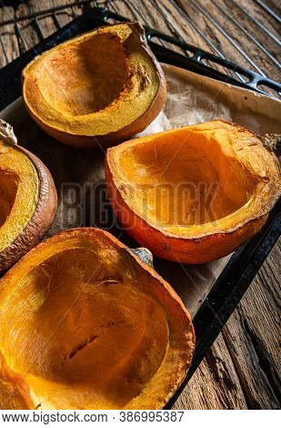 Halves Of Homemade Baked Orange Pumpkins On Baking Sheet, On Oven Tray And On Natural Textured Woode