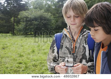 Dois rapazes jovens com mochilas usando a bússola