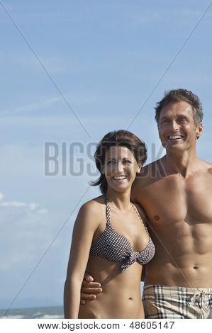Portret szczęśliwa para semidressed odwracając przeciwko niebo na plaży