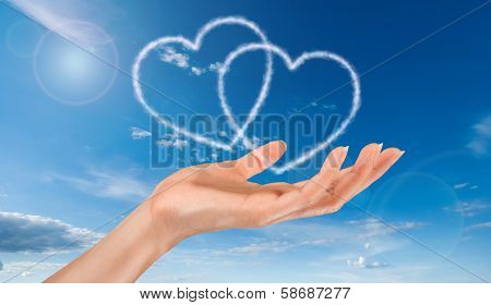 woman hand and heart shaped clouds