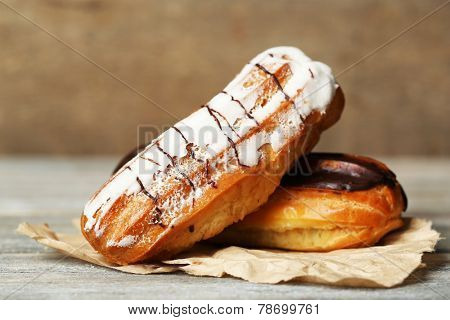Tasty eclairs on wooden table, close up