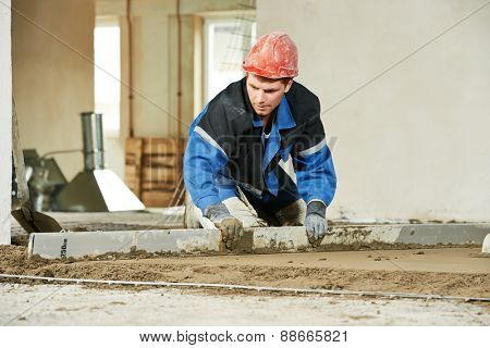 Plasterer doing indoors concrete cement floor topping with float
