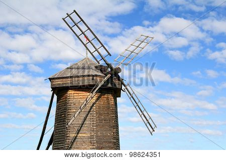 Old wooden windmill over blue cloudy sky