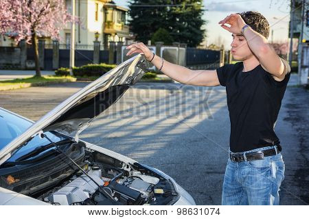 Handsome young man trying to repair a car engine