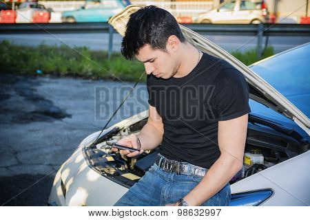 Man trying to repair car and seeking help on phone