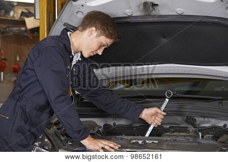 Apprentice Mechanic In Auto Shop Working On Car Engine