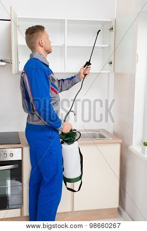 Worker Spraying Insecticide On Shelf