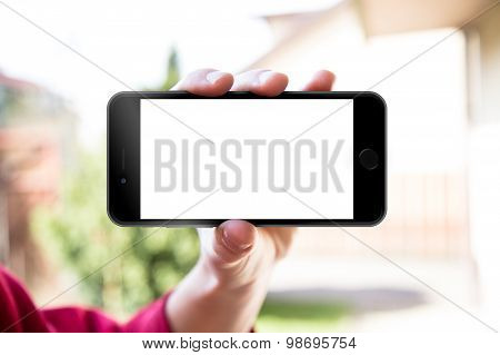 Man's hand shows mobile smartphone in horizontal position, blurred background