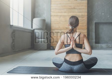 Young woman in yoga class making asana exercises. Girl do Reverse Prayer Pose, back and shoulders stretching. Healthy lifestyle in fitness club.