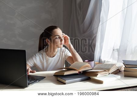 girl reading a book and drinking coffee works at the computer