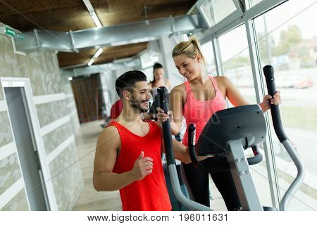 Attractive woman working cardio exercises with personal trainer in gym