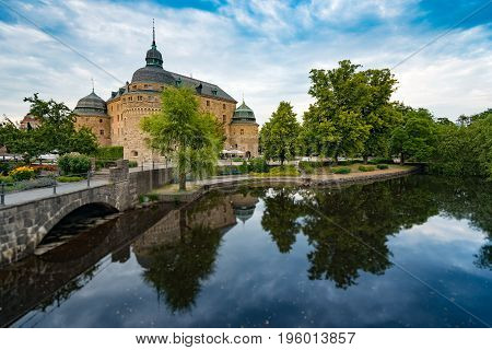 Old medieval castle in Orebro Sweden Scandinavia Europe. Landmark in foreground and blue cloudy sky in background. Architecture and travel.