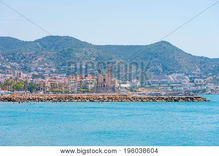 Stony Beach And Church Of Sant Bartomeu And Santa Tecla In Sitges, Barcelona, Catalunya, Spain. Copy
