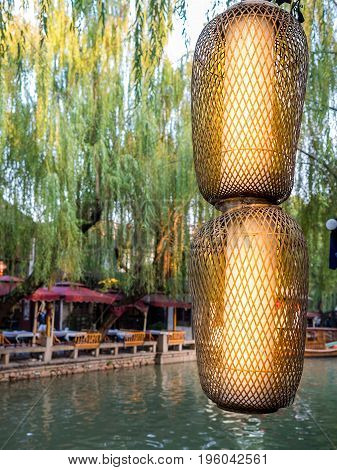 Suzhou, China - Nov 5, 2016: Brightly lit Chinese lanterns in front of waterway and willows at the historic Zhouzhuang Water Town.