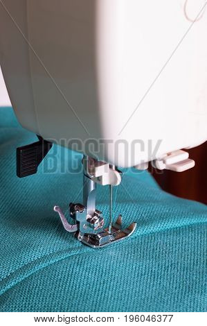 Close up of sewing machine working with turquoise fabric