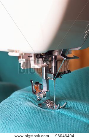 Close up of sewing machine working with turquoise fabric