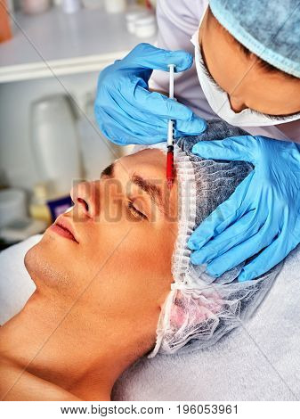 Filler injection for male face. Plastic facial surgery in beauty clinic. Man anti-aging therapy for complexion. Doctor in medical gloves with syringe forehead injects. Removal of skin defects.