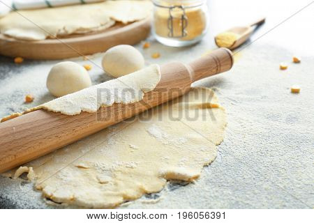 Unleavened dough for tortillas with rolling pin on kitchen table